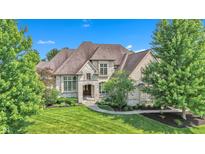 Elegant stone home featuring a lush green lawn, mature trees, and a welcoming arched entrance at 10471 Winghaven Dr, Noblesville, IN 46060