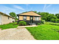 Charming bungalow with fresh black and tan exterior paint, complimented by the green grass in the front yard at 1513 S Rural St, Indianapolis, IN 46203