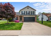 Charming two-story home featuring a brick front, black shutters, two-car garage, and a well-manicured lawn at 1605 Perry Commons Blvd, Indianapolis, IN 46217