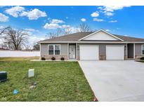 Charming townhouse featuring gray siding, a two-car garage, and a well-manicured lawn at 1612 Paula Dr, Columbus, IN 47201