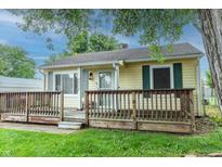 Charming one-story home with yellow siding, green shutters, a covered front porch, and mature trees at 2620 13Th St, Columbus, IN 47201