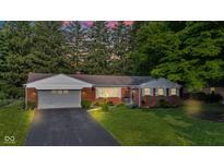 Dusk view of a red brick home with an attached garage, highlighting the well-lit exterior and inviting ambiance at 703 Chapel Hill W Dr, Indianapolis, IN 46214