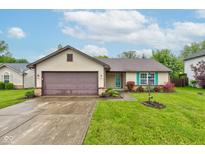 Charming ranch-style home featuring a two-car garage, well-maintained lawn, and colorful flower beds at 7918 Bitternut Dr, Indianapolis, IN 46236