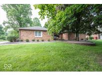 Charming brick home featuring lush green lawn and mature trees, nestled on a well-manicured lot at 9133 Log Run N Dr, Indianapolis, IN 46234