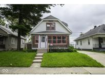 Charming home featuring a well-manicured lawn, brick accents, and a welcoming entrance at 1115 N Kealing Ave, Indianapolis, IN 46201