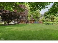 Landscaped front yard with mature trees and a stone house facade exudes a warm and inviting curb appeal at 1810 S Raceway Rd, Indianapolis, IN 46231