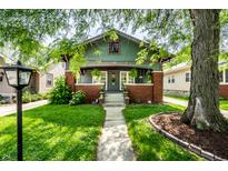 Charming home with green siding, brick accents, front garden and covered porch at 33 N Webster Ave, Indianapolis, IN 46219