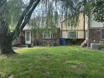 A charming backyard features a lush lawn, brick accents, and a large tree adding to the outdoor scenery at 5941 Deerwood Ct, Indianapolis, IN 46254