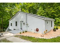 Cozy home featuring light gray siding, a metal roof and inviting entry with Welcome sign, set amidst a lush green backdrop at 8576 Riser Dr, , IN 46164