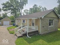 Charming single-story home with stone accents, a quaint front porch, and detached garage at 927 Cecil Ave, Indianapolis, IN 46219