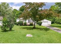 Charming single-story home featuring a lush front yard, wooden porch, and detached garage at 1727 S Irvington Ave, Indianapolis, IN 46203