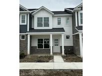 Charming townhome with white siding, stone accents, covered porch, and sidewalk at 19571 Grassy Branch Dr, Westfield, IN 46074