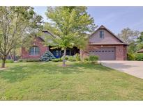 Inviting brick home featuring a blue door and a well-manicured lawn at 214 W Stoney Trl, Greenfield, IN 46140