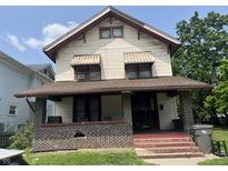 A two-story home with a covered front porch and awnings over the windows at 24 Hendricks Pl, Indianapolis, IN 46201