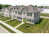 Charming townhome showcasing beautiful brickwork, manicured lawn, and inviting balcony at 2892 Maricopa Blvd, Whitestown, IN 46075