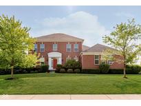 Beautiful two-story brick home with a manicured lawn and bright red front door at 4617 S Cobblestone Dr, Zionsville, IN 46077