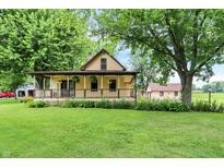 Inviting home featuring a charming front porch, lush green lawn, and mature trees at 6644 Mcfarland Rd, Indianapolis, IN 46227