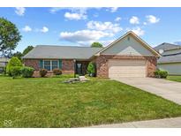 Charming brick home featuring a well-maintained lawn, lush landscaping, and an attached two-car garage at 11026 Clearspring Way, Indianapolis, IN 46239