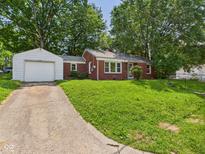 Charming brick home featuring a detached garage and a well-maintained lawn at 220 Central Ave, Anderson, IN 46012