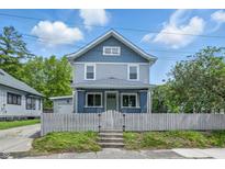 Charming two-story home featuring a fenced front yard, a light blue exterior and a welcoming covered porch at 2896 Sutherland Ave, Indianapolis, IN 46205