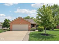 Charming brick home featuring a two-car garage, well-manicured lawn, and mature landscaping at 3571 S Cedar Creek Ln, New Palestine, IN 46163