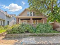 Charming home featuring a welcoming front porch with brick pillars and lush landscaping at 4709 E New York St, Indianapolis, IN 46201