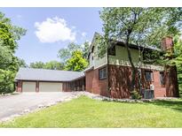 Charming home featuring a brick exterior, attached two car garage, and lush green lawn at 5530 Shawnee Trail South Dr, Indianapolis, IN 46220