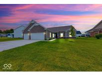 Charming single-story home with a brick facade and a well-manicured lawn at twilight at 59 Manchester Dr, Trafalgar, IN 46181