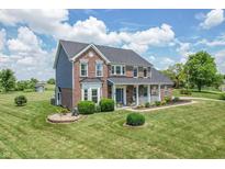 Lovely brick home with a manicured lawn, a welcoming front porch and mature trees in the background at 6702 W Willow Grove Dr, New Palestine, IN 46163