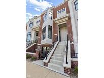 Inviting brick townhome exterior featuring a staircase leading to the front door and a bay window at 711 E 16Th St, Indianapolis, IN 46202