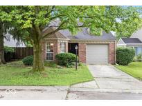 Charming brick home featuring an attached garage, mature trees, and a well-maintained front yard at 7743 Waterwood Dr, Indianapolis, IN 46214