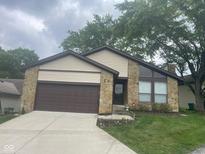 Charming home featuring a stone facade, attached garage, and well-manicured lawn at 7950 Eagle Valley Pass, Indianapolis, IN 46214