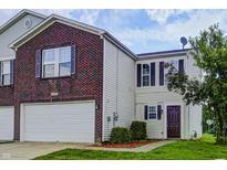 Two-story townhome features a brick facade, attached garage, and well-maintained landscaping at 8030 Cork Bend Ln, Indianapolis, IN 46239