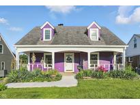 Charming purple two-story home featuring a welcoming front porch and beautifully landscaped front yard at 808 N Layman Ave, Indianapolis, IN 46219