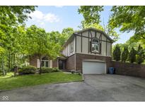 Charming two-story Tudor-style home with brick and siding, lush landscaping, and a two-car garage at 8310 Fall Creek Rd, Indianapolis, IN 46256