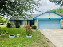 Charming single Gathering home featuring stone accents, a blue garage door and lush landscaping at 8318 Rob Ln, Indianapolis, IN 46237