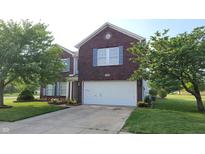 Charming brick two-story home featuring an attached garage, beautiful landscaping, and manicured front lawn at 10042 Pine Grove Way, Indianapolis, IN 46234