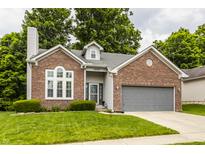 Charming brick home with manicured lawn, gray roof, an attached garage and lush green landscaping at 10380 Sand Creek Blvd, Fishers, IN 46037