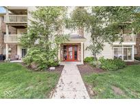 Inviting condo entrance featuring well-maintained landscaping, red door, and a welcoming pathway at 1044 Timber Creek Dr # 2, Carmel, IN 46032