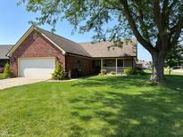Charming brick home with a well-manicured lawn, mature trees, and a two-car garage at 10976 Mt Vernon N Trl, Indianapolis, IN 46229