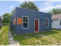 Charming home featuring vertical siding, a red front door, and complemented by landscaped surroundings at 1409 N Grant Ave, Indianapolis, IN 46201