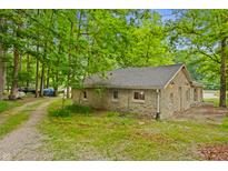 Stone cottage with mature trees, a gravel driveway, and a well-maintained landscape at 4418 North Dr, Quincy, IN 47456