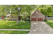 Charming brick home features a well-manicured lawn, mature trees, and a two-car garage at 5037 Surrey Ln, Carmel, IN 46033