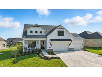 Stunning two-story home featuring white siding, black accents, a covered porch, and a three-car garage at 5668 Champion Way, Greenwood, IN 46143