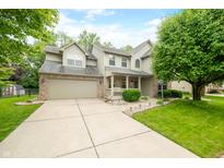 Two story home featuring a two car garage, green lawn, mature landscaping, and inviting porch at 7833 Meadow Bend Dr, Indianapolis, IN 46259