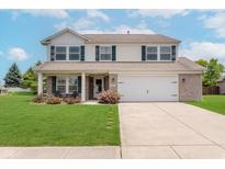 Charming two-story home featuring a well-manicured lawn, attached garage, and inviting front porch with decorative landscaping at 985 Farmington Trl, Brownsburg, IN 46112