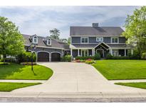 Beautiful two-story home showcasing dark siding, metal roof accents, and a spacious driveway leading to a three-car garage at 10974 Harbor Bay Dr, Fishers, IN 46040