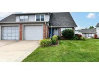 Charming townhome with a lush green lawn, colorful flower beds, and an attached one-car garage at 1124 Paradise Ct # B, Greenwood, IN 46143