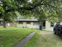 Charming single-story home with light yellow paint, shutters and a spacious front yard with mature trees at 1308 Phillips Dr, Indianapolis, IN 46241