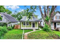 Charming green home with a welcoming front porch and well-maintained lawn and landscaping at 1338 N Parker Ave, Indianapolis, IN 46201